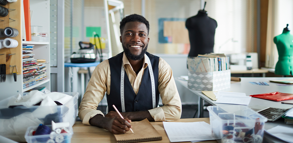 A self-employed man works in his office as a tailor.