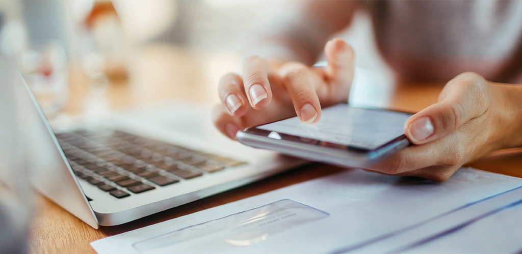 Woman working on phone and laptop